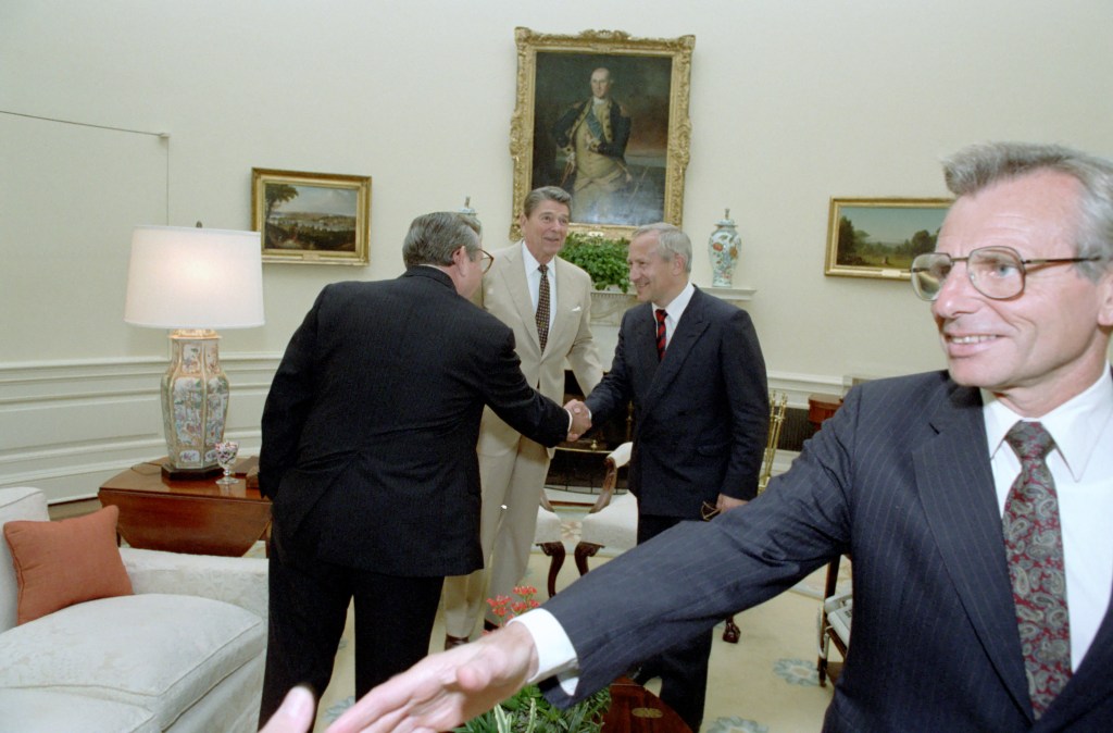 Carlucci reaging out in foreground.  Reagan introduces Baker to Gordievsky.