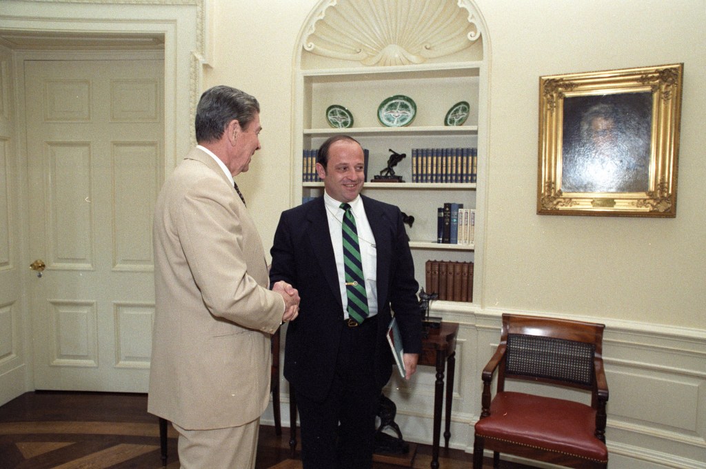 Reagan meeting an "unidentified man," according to the original caption.  Note the visitors badge.