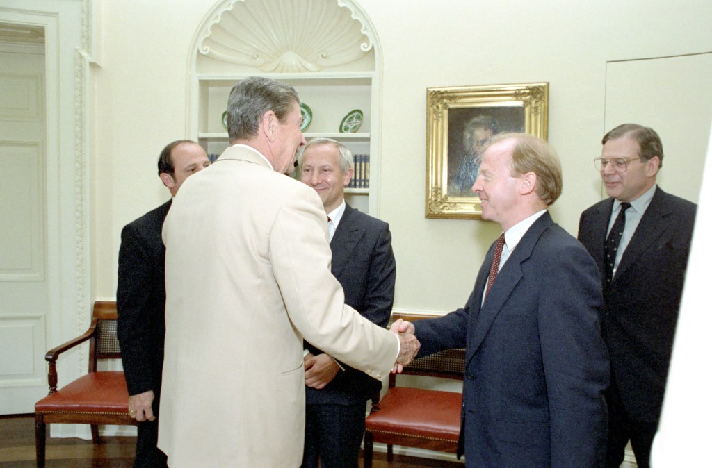 Reagan shaking a second undentified man's hand as Oleg Gordievsky Watches.  